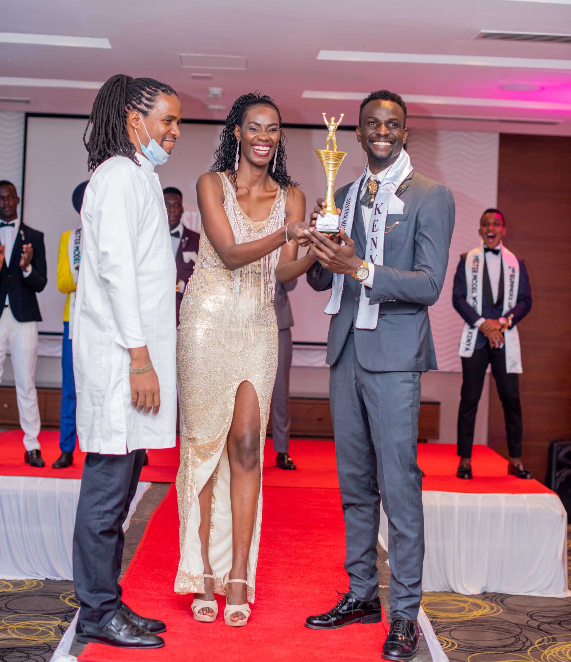 Mr. Wordwide Kenya winner Branham Otieno receiving the winner's trophy at the crowning event of the competition